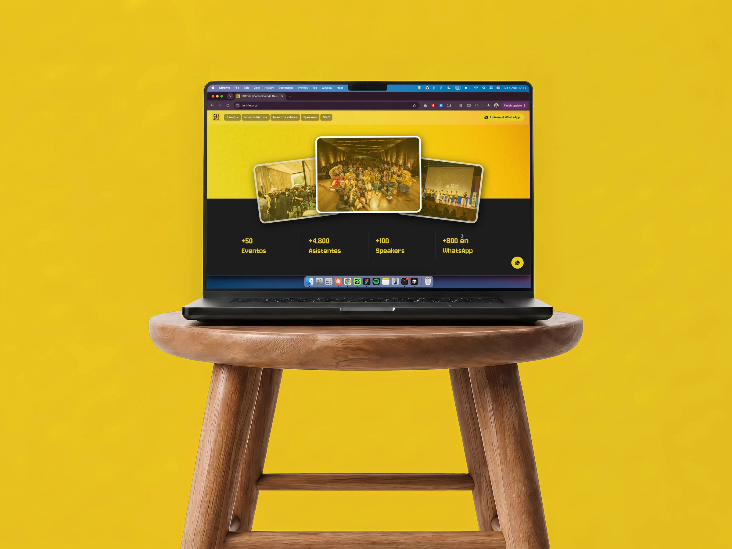 Mockup de la landing page de JSChile en MacBook Pro sobre banco de madera, con fondo amarillo.