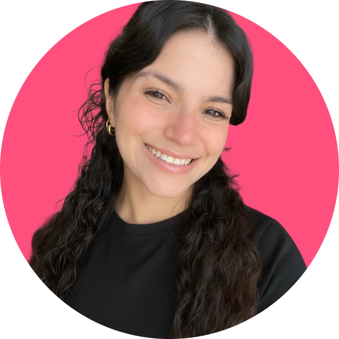 Mujer joven con cabello largo y rizado sonriendo sobre un fondo rosa.