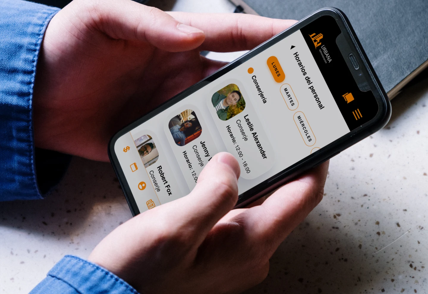 Persona sosteniendo un smartphone con la app Urbana Administración abierta en la sección de horarios del personal del edificio.