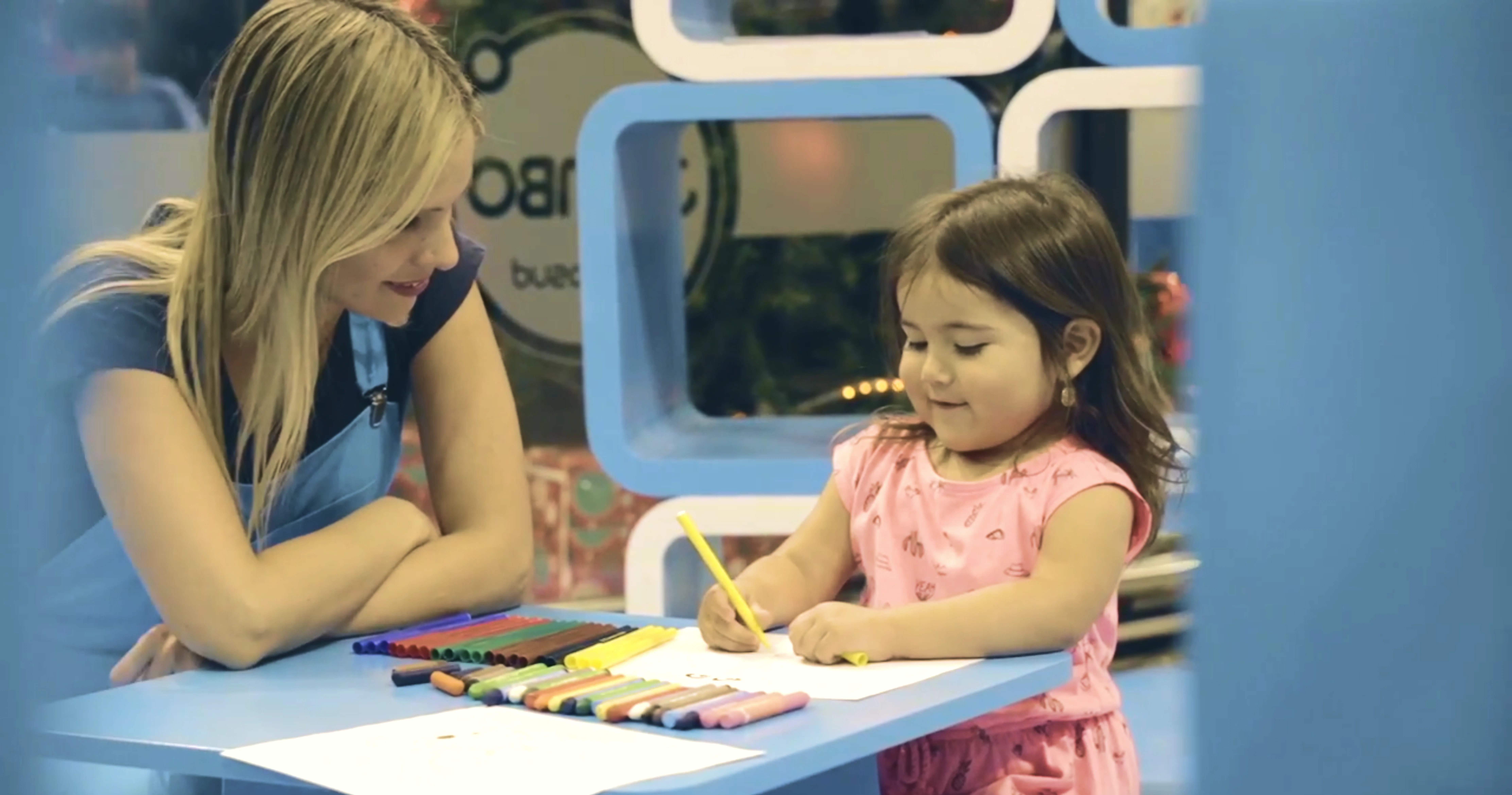 Promotora Vital Kids dibujando con una niña en una mesa de activación en el punto de venta.