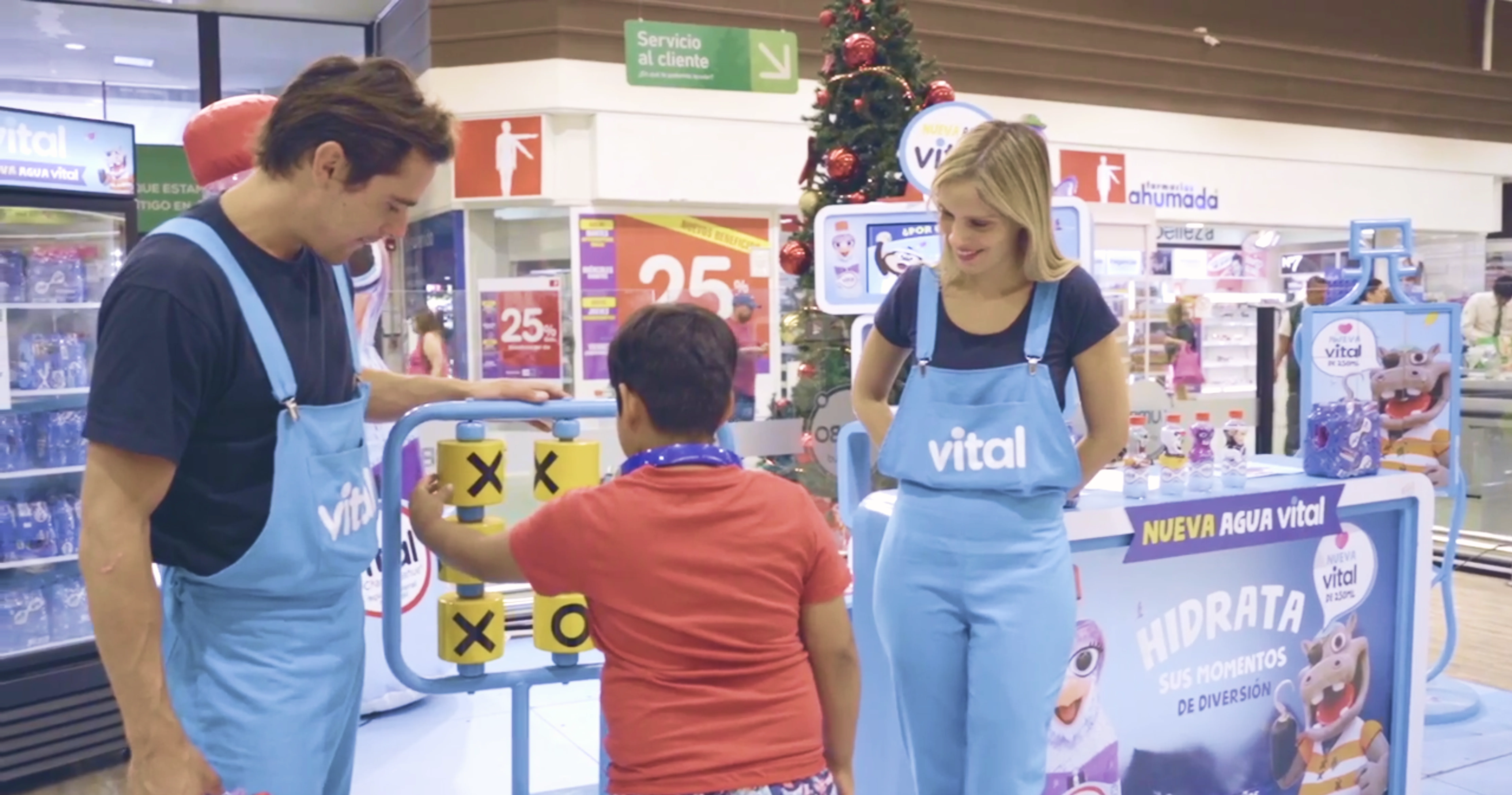 Niño jugando al gato en el stand Vital Kids con un promotor y una promotora acompañándolo.